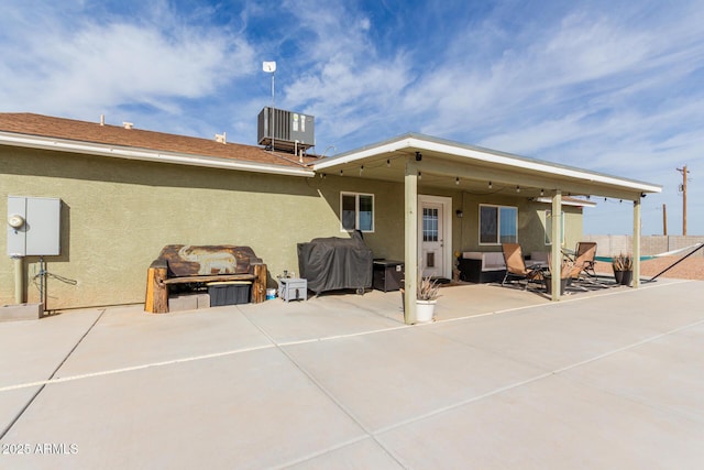 rear view of property featuring a patio, central AC, and stucco siding