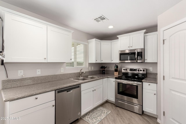 kitchen featuring a sink, visible vents, light wood-style floors, white cabinets, and appliances with stainless steel finishes