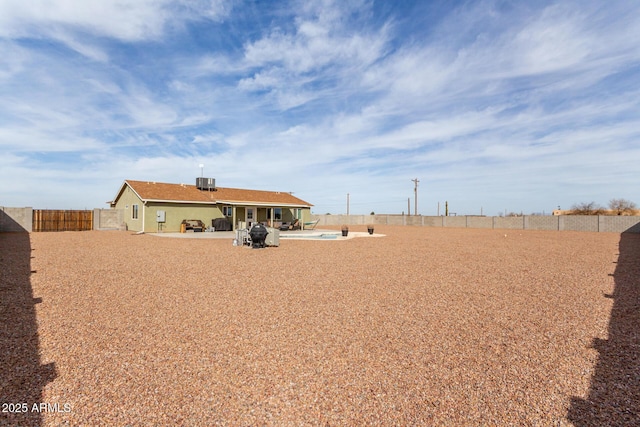 view of yard with a patio area, a fenced backyard, central AC, and a gate