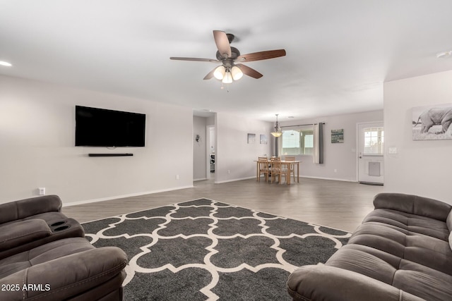 living area with ceiling fan, baseboards, and wood finished floors