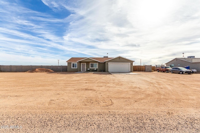 ranch-style house featuring an attached garage, dirt driveway, fence, and stucco siding