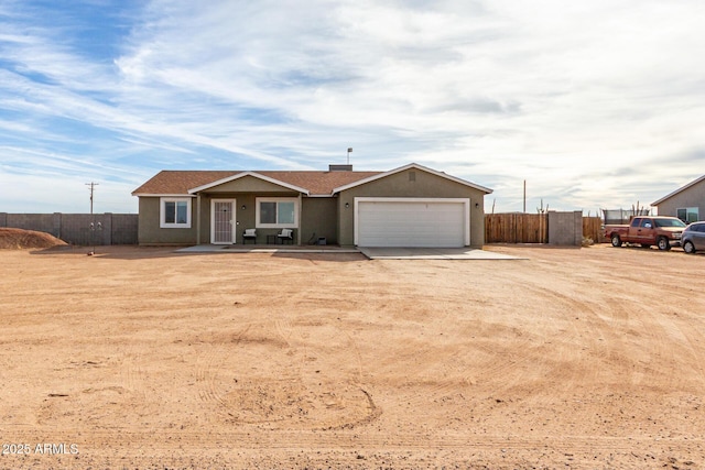 ranch-style home with a garage, fence, dirt driveway, and stucco siding