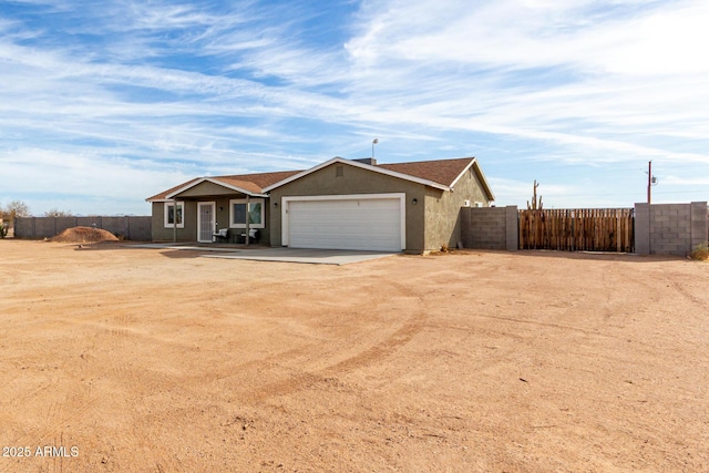 ranch-style house featuring a garage, stucco siding, driveway, and fence