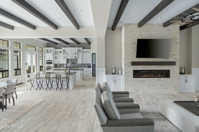 living room with a fireplace, beamed ceiling, and light hardwood / wood-style floors