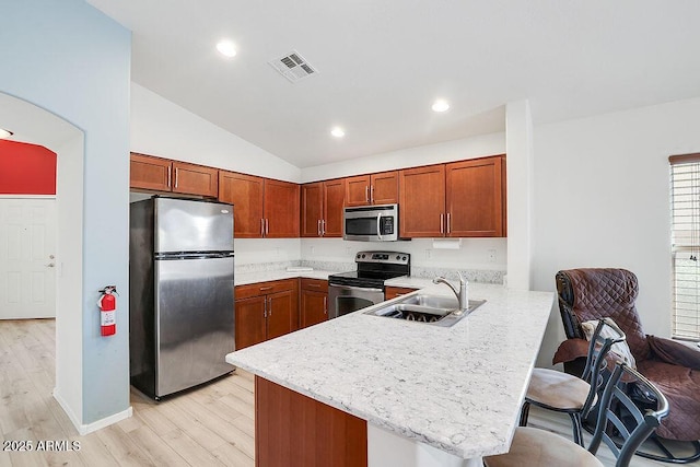 kitchen with a peninsula, visible vents, a sink, stainless steel appliances, and a breakfast bar area