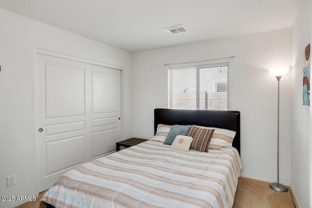 carpeted bedroom with visible vents, a closet, and baseboards