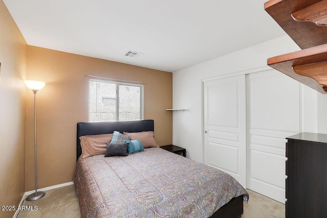 bedroom with a closet, light colored carpet, baseboards, and visible vents