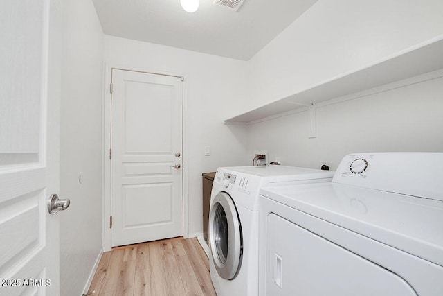 laundry area featuring visible vents, baseboards, light wood-style floors, laundry area, and washing machine and dryer