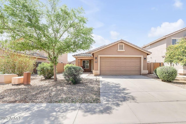 view of front of home with stucco siding, driveway, a garage, a tiled roof, and fence