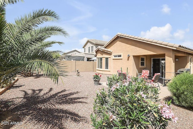 rear view of house featuring a tiled roof, fence, a patio, and stucco siding