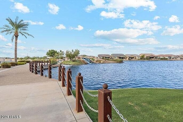 view of dock featuring a water view and a yard