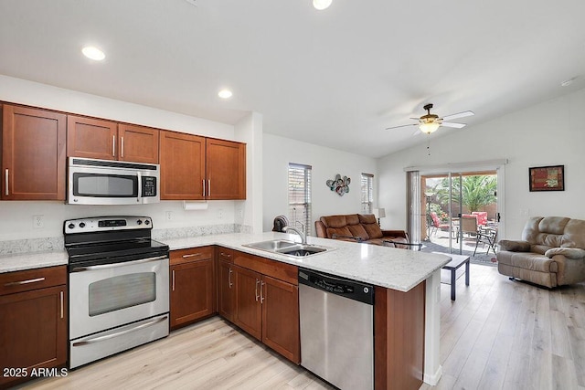 kitchen with a sink, open floor plan, a peninsula, and stainless steel appliances