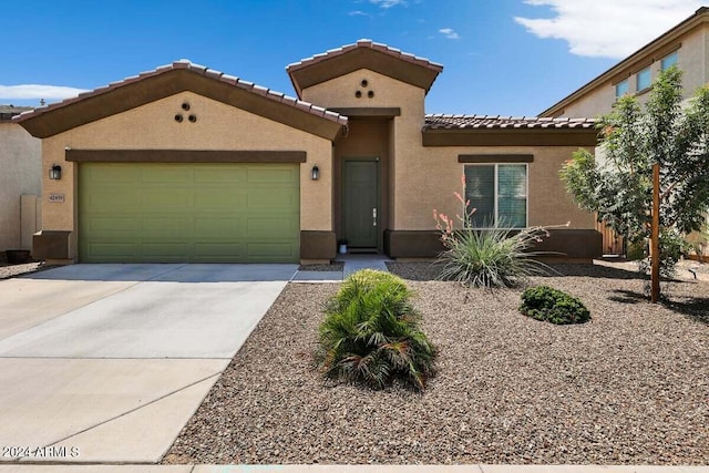 view of front of house featuring a garage, concrete driveway, a tile roof, and stucco siding