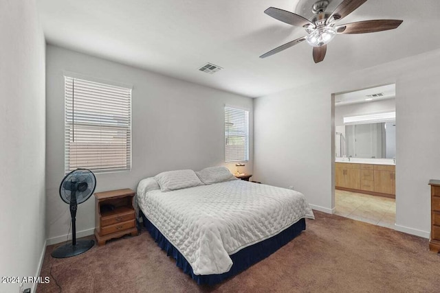 bedroom with light carpet, ensuite bath, visible vents, and baseboards