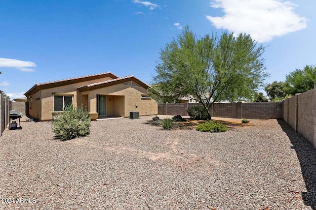 rear view of property featuring central air condition unit, a tile roof, a fenced backyard, and stucco siding