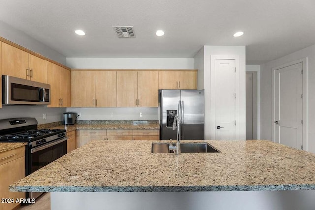 kitchen featuring a sink, stainless steel appliances, light stone counters, and light brown cabinets