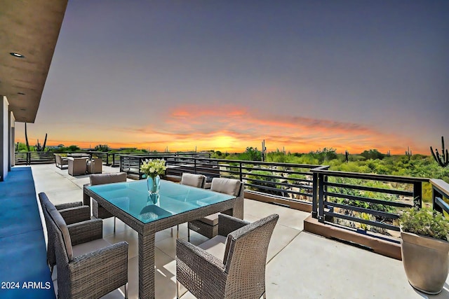 patio terrace at dusk featuring a balcony