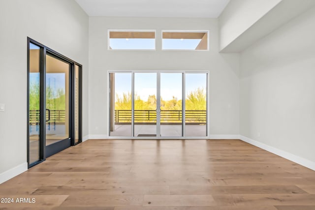 empty room featuring light wood-type flooring and a high ceiling