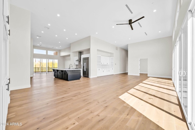 unfurnished living room featuring ceiling fan, light wood-type flooring, built in features, and sink