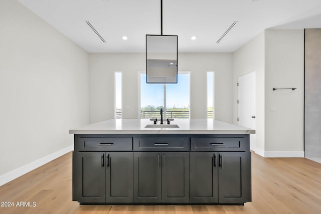 kitchen with decorative light fixtures, light wood-type flooring, sink, and a kitchen island