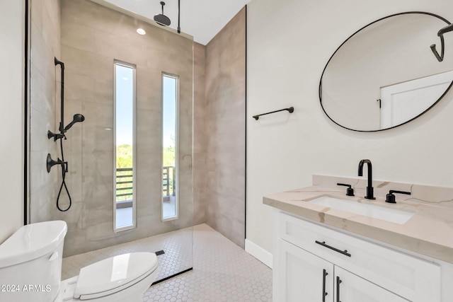 bathroom featuring a tile shower, tile patterned flooring, vanity, and toilet