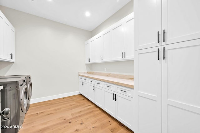 laundry room featuring cabinets, light hardwood / wood-style flooring, and washing machine and dryer