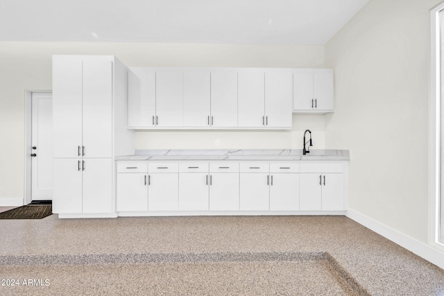 kitchen featuring white cabinetry, sink, and light stone counters