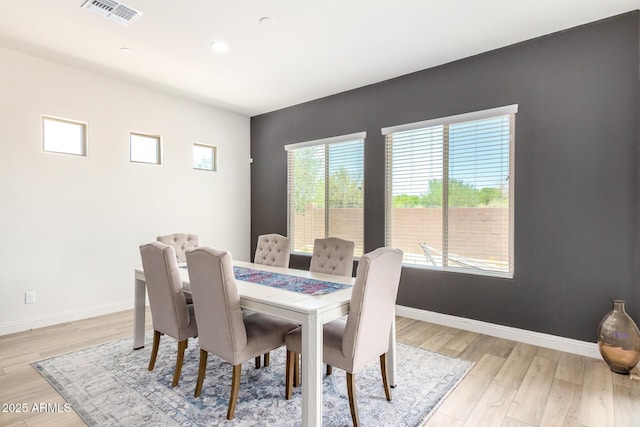 dining room featuring visible vents, baseboards, and light wood finished floors