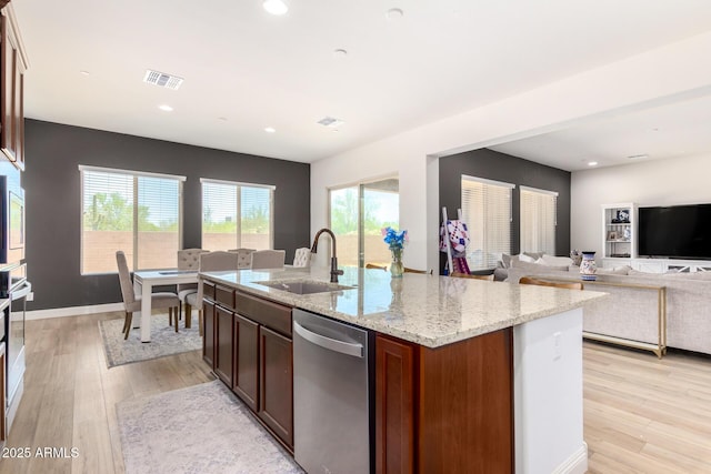 kitchen with stainless steel dishwasher, light wood-type flooring, visible vents, and a sink