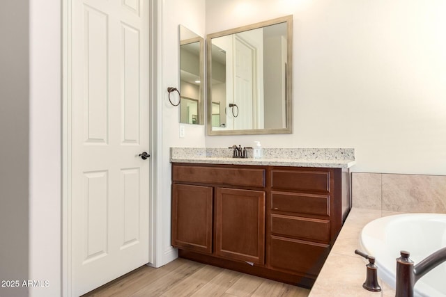 full bath with a bath, vanity, and wood finished floors