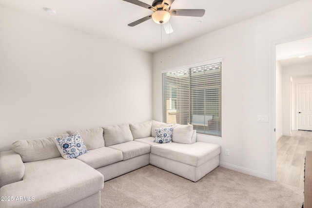 living area featuring light carpet, baseboards, and ceiling fan