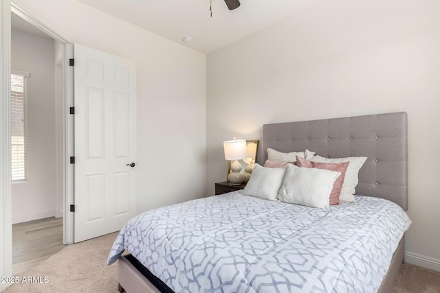 bedroom with light carpet, ceiling fan, and baseboards