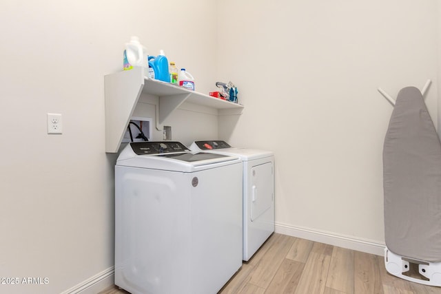 laundry area with baseboards, washing machine and dryer, laundry area, and light wood finished floors