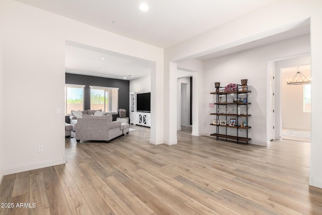 living area featuring light wood finished floors, recessed lighting, an inviting chandelier, and baseboards