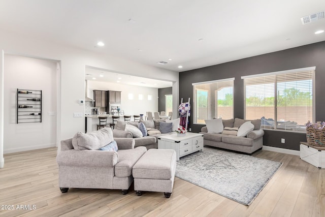 living room with recessed lighting, visible vents, baseboards, and light wood finished floors