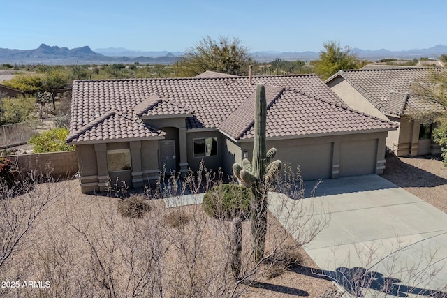 mediterranean / spanish-style home featuring a garage, a tile roof, a mountain view, and stucco siding