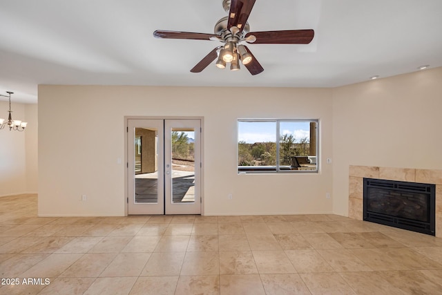 unfurnished living room featuring ceiling fan with notable chandelier, light tile patterned flooring, and a tile fireplace