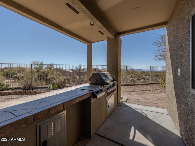 view of patio / terrace featuring area for grilling, fence, visible vents, and an outdoor kitchen