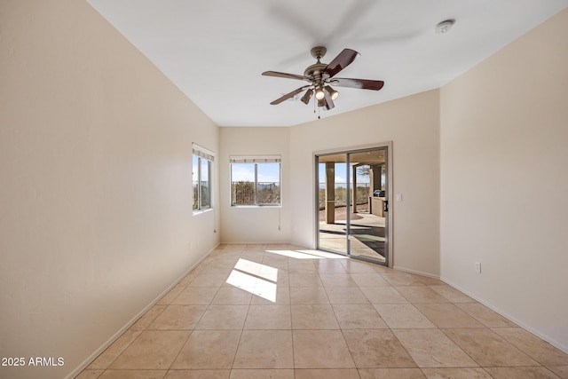empty room with a ceiling fan, baseboards, and light tile patterned floors