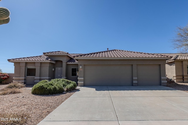 mediterranean / spanish home featuring concrete driveway, a tiled roof, an attached garage, and stucco siding