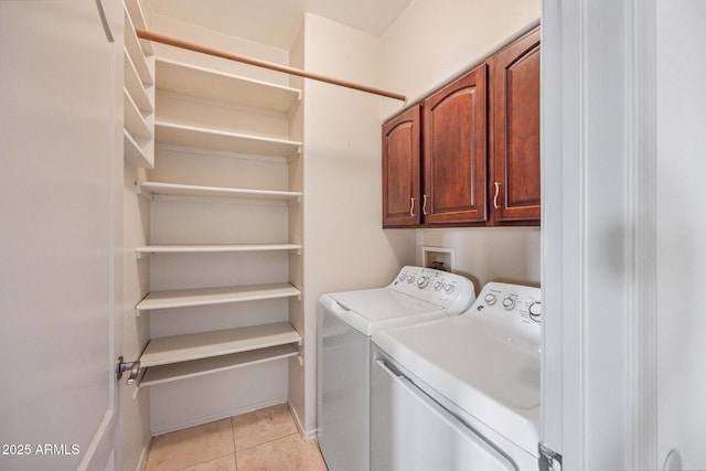 laundry area with light tile patterned floors, washer and clothes dryer, cabinet space, and baseboards
