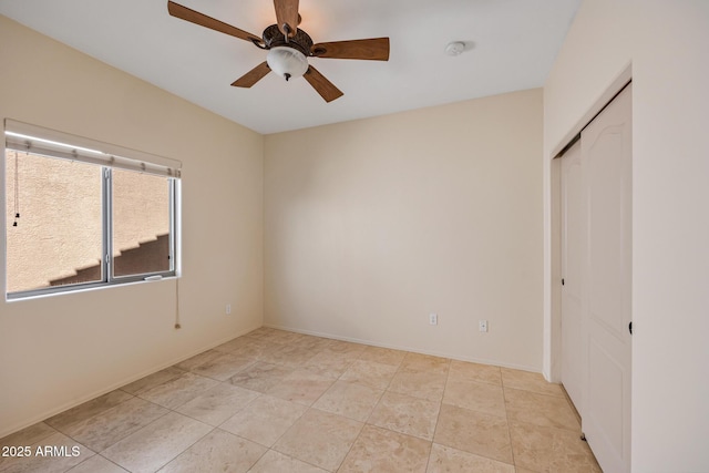 unfurnished bedroom featuring a ceiling fan, a closet, baseboards, and light tile patterned floors