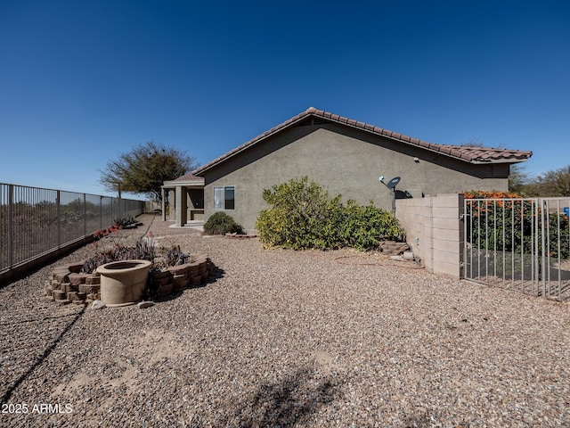 view of property exterior featuring a fenced backyard, a tile roof, and stucco siding
