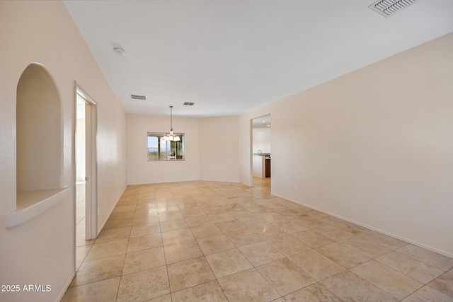 spare room with light tile patterned floors, visible vents, and a chandelier