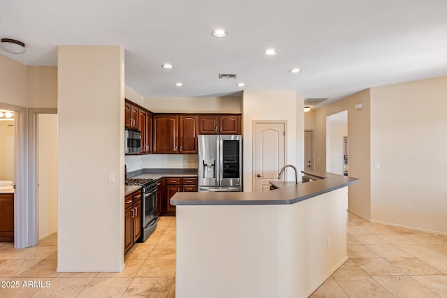 kitchen with visible vents, appliances with stainless steel finishes, dark countertops, and a kitchen island with sink