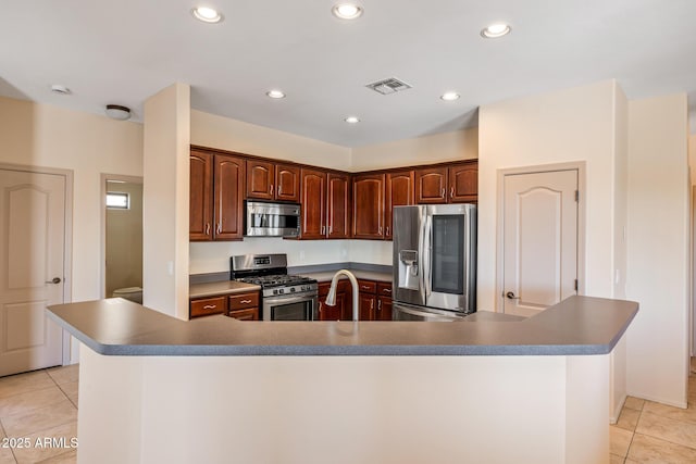 kitchen featuring light tile patterned floors, appliances with stainless steel finishes, a large island with sink, and recessed lighting