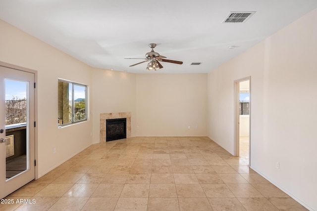 unfurnished living room with a ceiling fan, visible vents, a tiled fireplace, and light tile patterned flooring