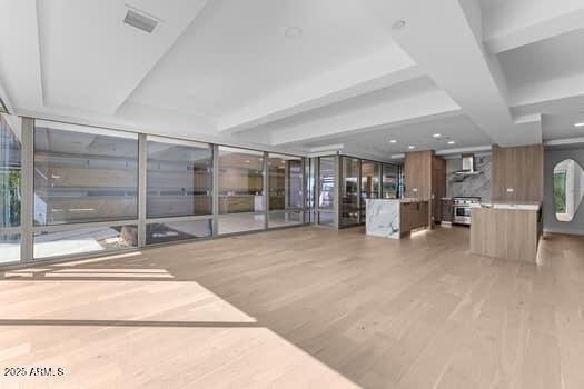 interior space featuring a wall of windows, visible vents, beam ceiling, and light wood finished floors