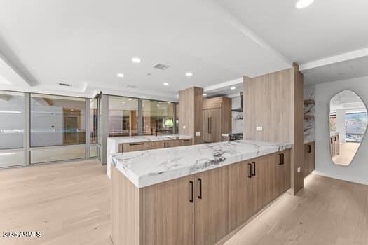 kitchen featuring light stone counters, recessed lighting, light wood-style floors, brown cabinetry, and modern cabinets