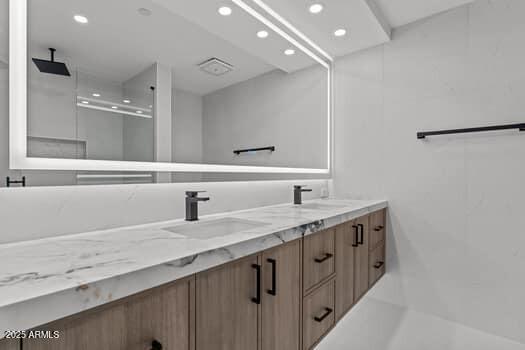 full bathroom with a sink, a shower stall, recessed lighting, and double vanity